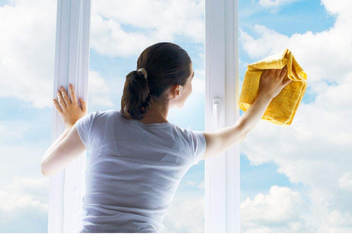 Ragazza pulisce vetri delle finestre